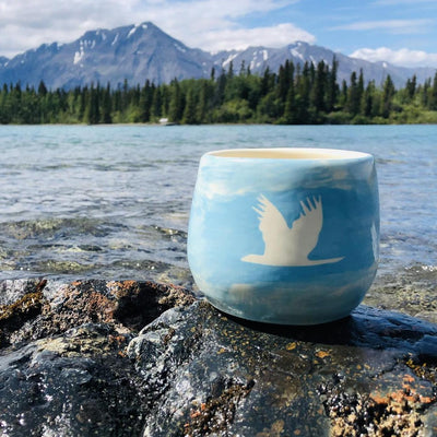 swan mug sitting next to river in yukon